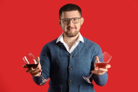Photo for Young sommelier holding glasses with different types of wine on red background - Royalty Free Image