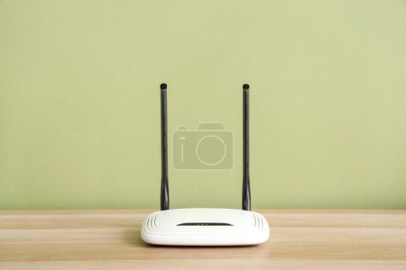 Modern wi-fi router on shelf near green wall