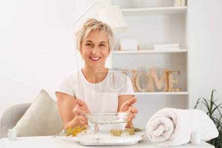 Photo for Mature woman doing steam inhalation in bedroom - Royalty Free Image
