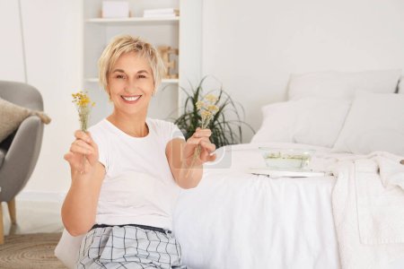 Photo for Mature woman with herbs for steam inhalation in bedroom - Royalty Free Image