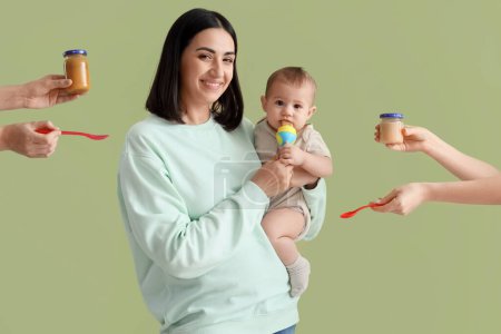 Young woman giving her little baby nibbler and hands with puree on green background