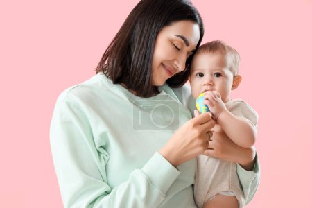 Mujer joven dando a su bebé mordisquear con comida sobre fondo rosa, primer plano
