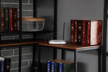 Modern wi-fi router on bookshelf in dark room