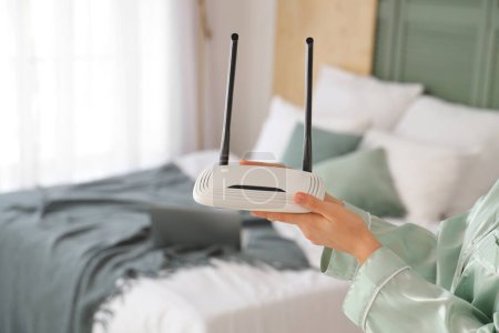 Woman with wi-fi router in bedroom, closeup
