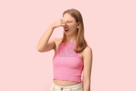 Photo for Young woman feeling terrible smell on pink background - Royalty Free Image
