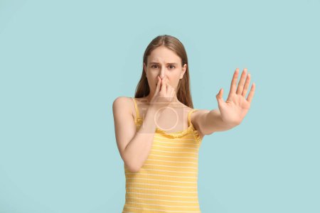 Photo for Young woman pinching nose because of disgusting smell on blue background - Royalty Free Image