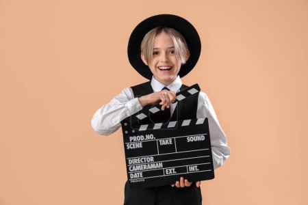 Téléchargez les photos : Petit acteur avec film clapper sur fond beige - en image libre de droit