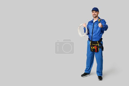 Foto de Retrato de electricista masculino con alambres y crimper sobre fondo gris - Imagen libre de derechos