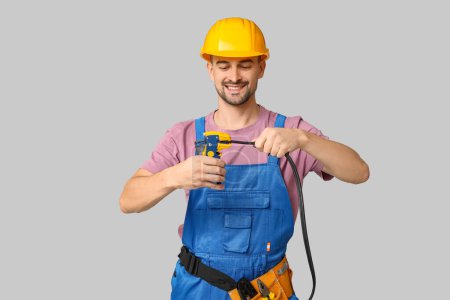 Foto de Retrato de electricista masculino con alambre y crimper sobre fondo gris - Imagen libre de derechos
