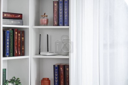 Bücherregal mit modernem WLAN-Router im Zimmer