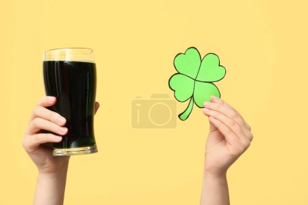 Photo for Hands with beer and clover on yellow background. St. Patrick's Day celebration - Royalty Free Image