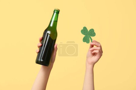 Photo for Hands with beer and clover on yellow background. St. Patrick's Day celebration - Royalty Free Image