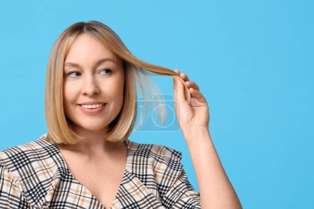 Glückliche junge Frau mit Bob-Frisur auf blauem Hintergrund
