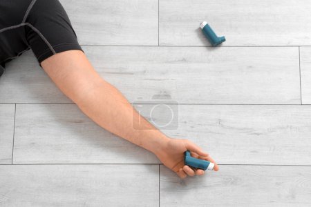 Téléchargez les photos : Jeune homme sportif avec inhalateurs couchés sur le sol dans la salle de gym, gros plan - en image libre de droit