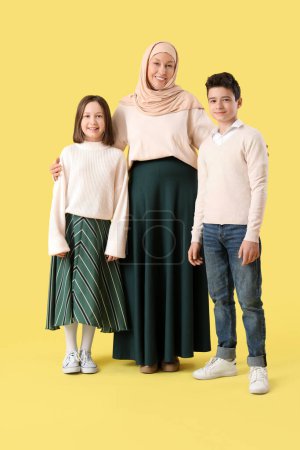 Glückliche muslimische Mutter mit ihren Kindern auf gelbem Hintergrund. Eid al-Fitr-Feier