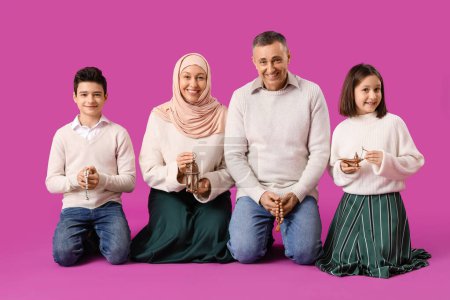 Happy Muslim family with traditional accessories on pink background. Eid al-Fitr celebration