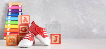 Foto de Zapatos de bebé con cubos sobre fondo grunge gris. Banner para el diseño - Imagen libre de derechos