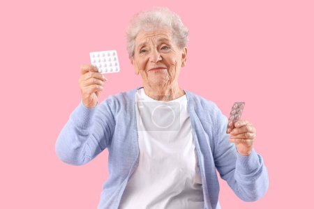 Foto de Mujer mayor con pastillas sobre fondo rosa - Imagen libre de derechos