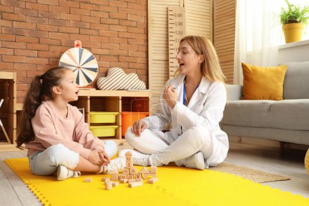 Mature speech therapist with logopedic probe and little girl in office