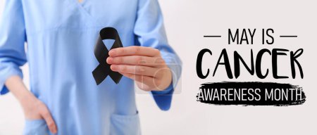 Photo for Doctor with black ribbon and text MAY IS CANCER AWARENESS MONTH on light background. Melanoma concept - Royalty Free Image