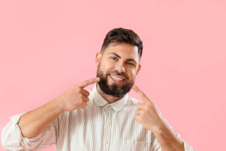 Young man with gum inflammation on pink background