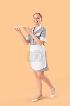 Camarera joven con plato vacío sobre fondo beige