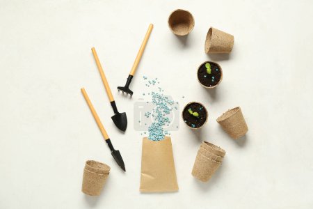 Outils de jardinage, pots à tourbe et sac avec engrais granulaire bleu sur fond blanc