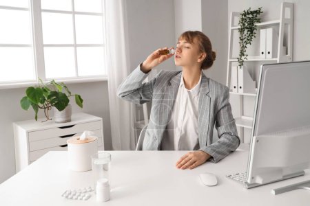 Téléchargez les photos : Ill jeune femme d'affaires en utilisant des gouttes nasales au bureau - en image libre de droit