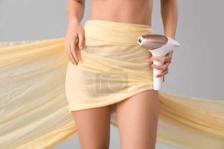 Photo for Beautiful young woman with photoepilator and fabric on grey background, closeup - Royalty Free Image