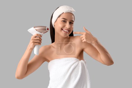 Photo for Beautiful young happy woman pointing at photoepilator on grey background - Royalty Free Image