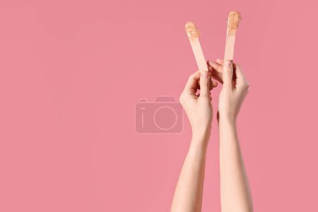 Photo for Female hands holding spatulas with sugaring paste on pink background - Royalty Free Image