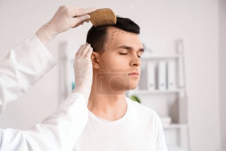 Doctor combing young man's hair in clinic, closeup