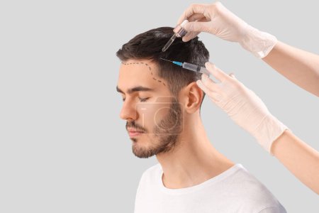 Photo for Young man receiving treatment for hair growth on light background, closeup - Royalty Free Image