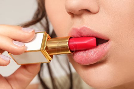 Schöne junge Frau mit rotem Lippenstift auf grauem Hintergrund, Nahaufnahme