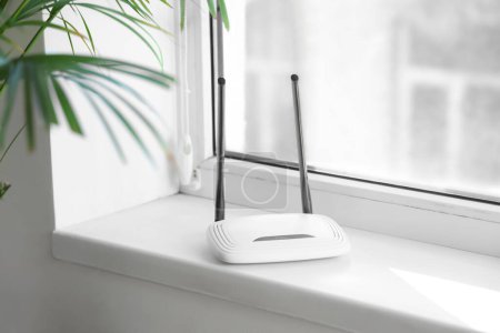 Modern wi-fi router on windowsill in light room, closeup