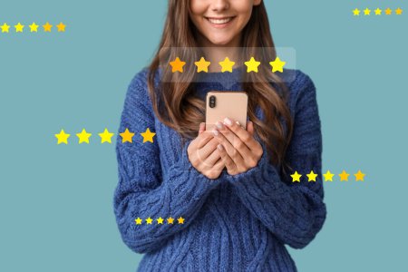Young woman giving rating to new mobile application on blue background