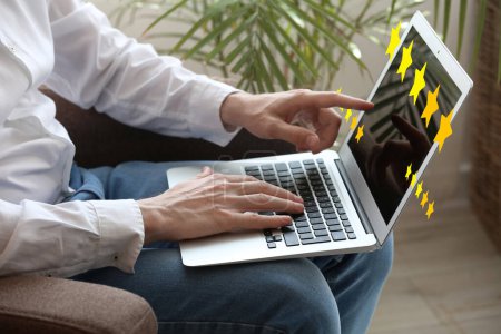 Man with laptop giving rating to new website at home