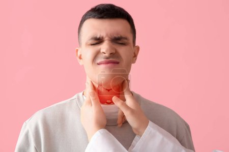 Endocrinologist examining thyroid gland of young man on pink background