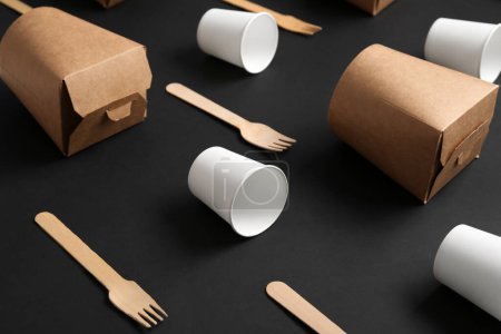Foto de Tazas de papel para llevar, cajas y tenedores sobre fondo negro - Imagen libre de derechos