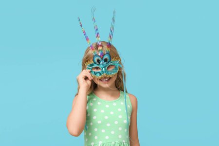Photo for Pretty little girl wearing carnival mask on blue background - Royalty Free Image