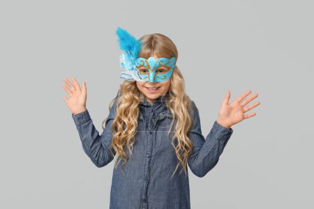 Photo for Funny little girl wearing carnival mask on light background - Royalty Free Image