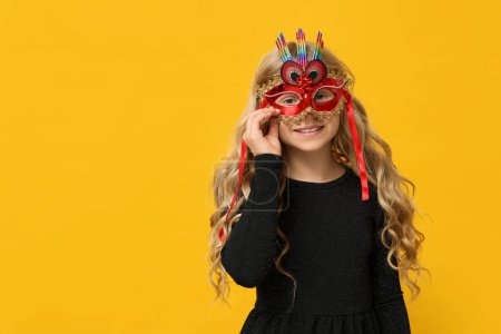 Photo for Pretty little girl wearing carnival mask on yellow background - Royalty Free Image