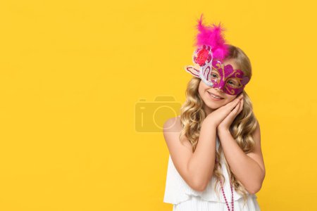 Photo for Adorable little girl wearing carnival mask on yellow background - Royalty Free Image
