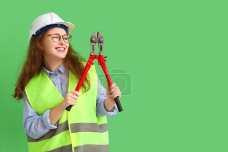 Photo for Female construction worker in eyeglasses with bolt cutter on green background - Royalty Free Image