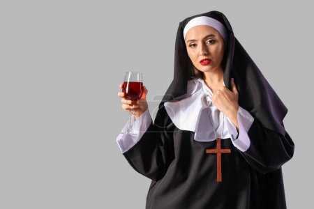 Freche Nonne mit einem Glas Wein auf hellem Hintergrund