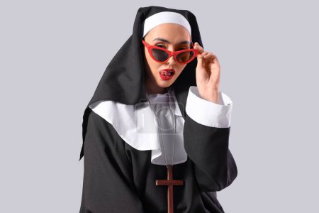 Sexy Nonne mit Sonnenbrille auf hellem Hintergrund