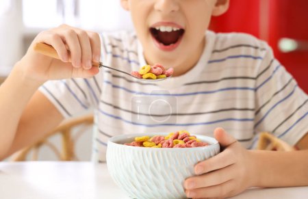 Petit garçon mangeant des anneaux de céréales à la maison