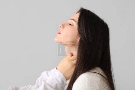 Photo for Endocrinologist examining thyroid gland of young woman on grey background - Royalty Free Image