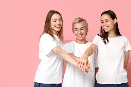 Mujeres poniendo las manos juntas sobre fondo rosa. Mujeres historia mes