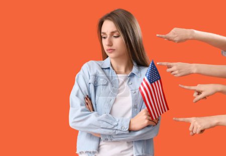 Menschen zeigen auf junge Frau mit USA-Flagge auf orangefarbenem Hintergrund. Anschuldigungskonzept